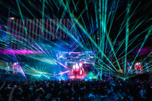 Lasers fill the sky illuminating the stage.